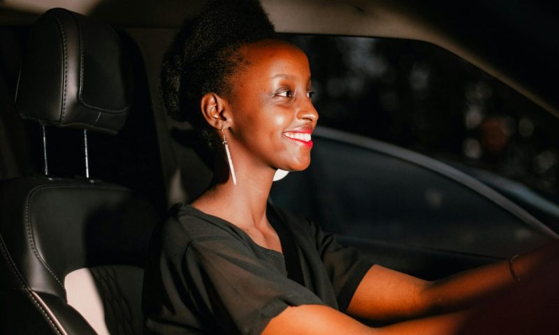 pexels-photo-9522173-9522173 A woman with black hair smiles while driving a car during sunset.